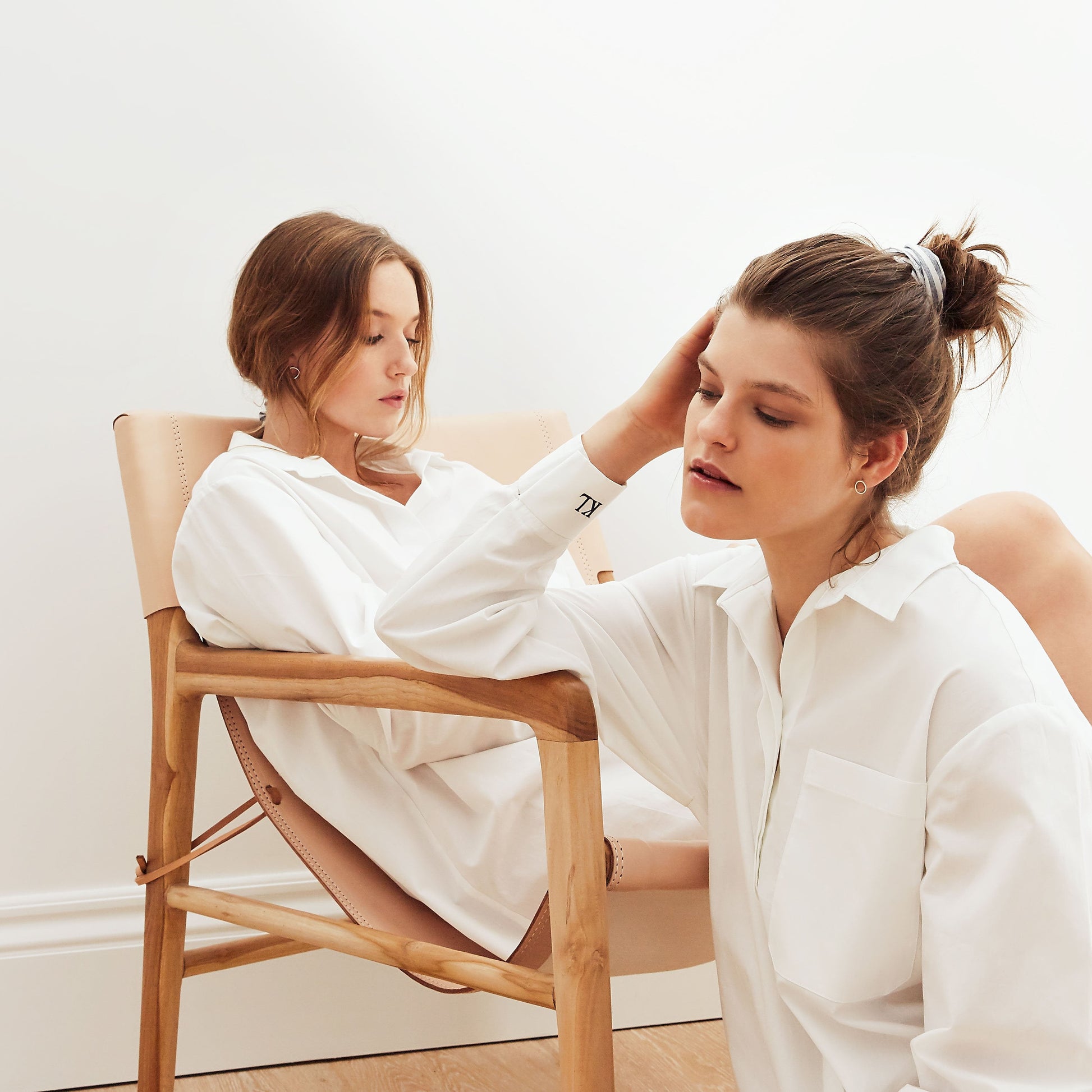 Two women wearing white shirt dresses