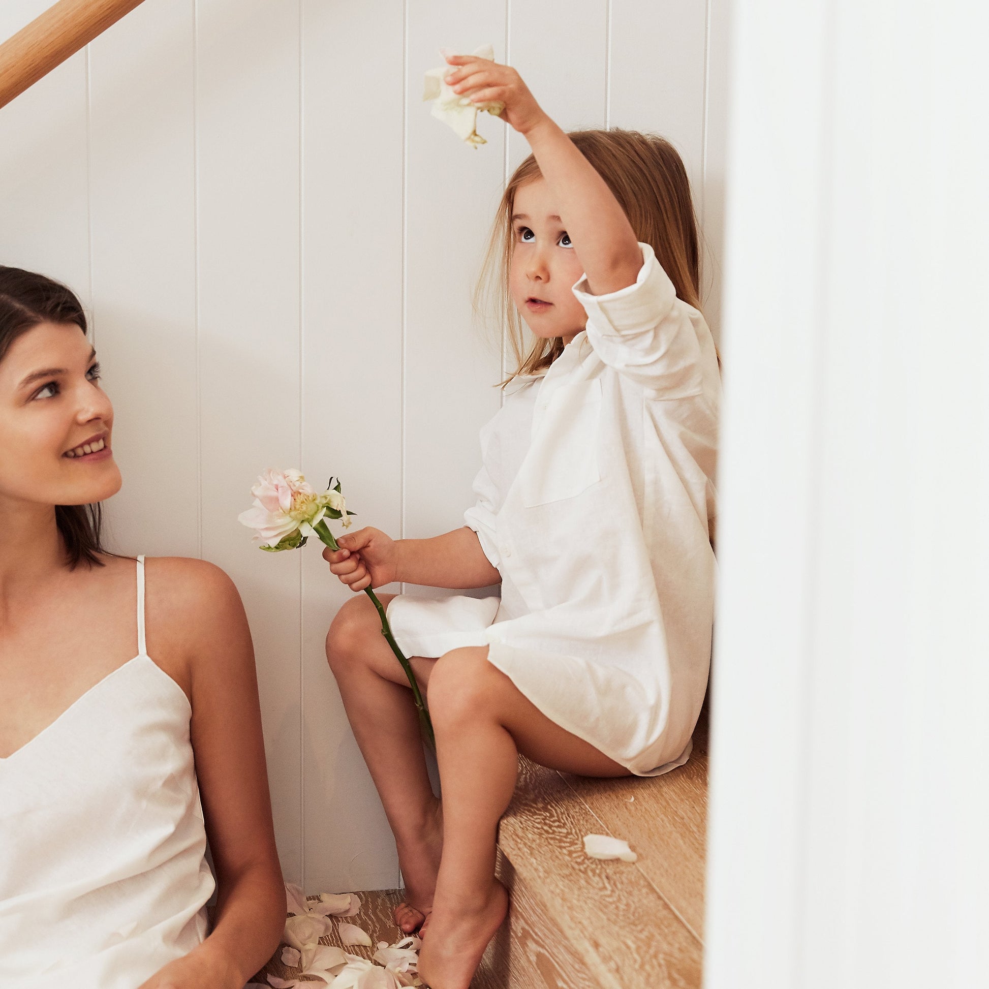 Girl wearing white shirt dress with flowers sat on the stairs