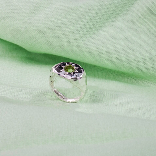 Silver signet ring with a pale green gen in the centre, surrounded by a sun shape