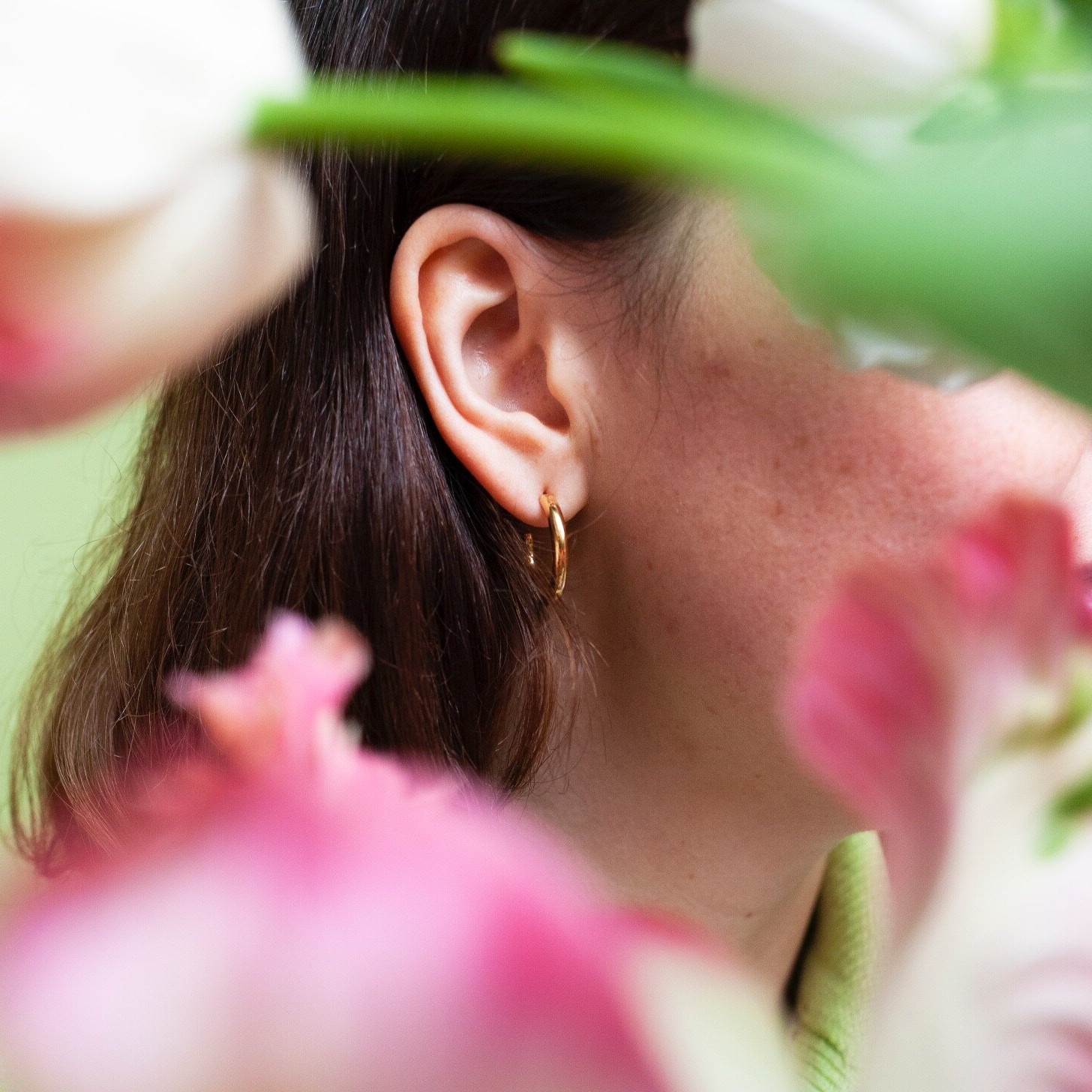 Close up of woman wearing small gold hoop earring