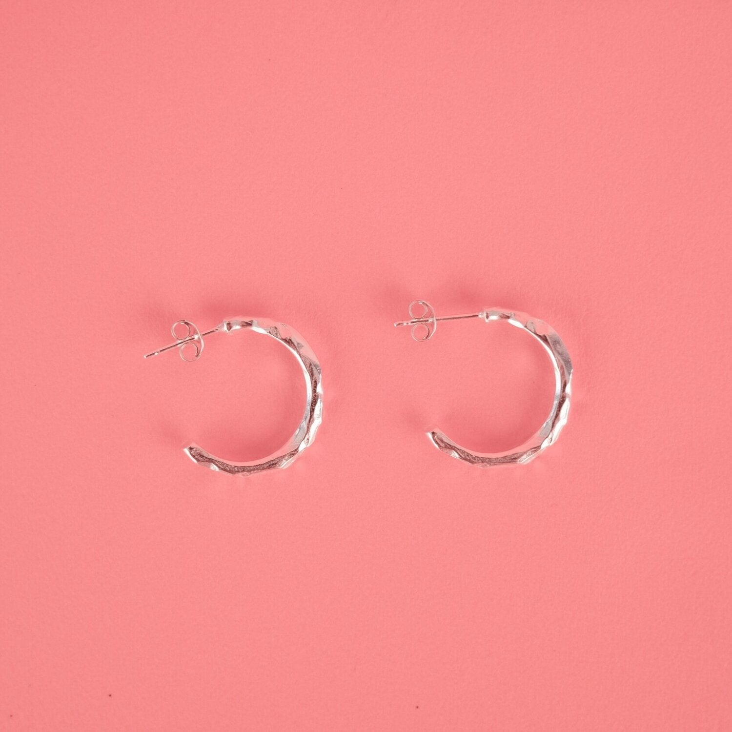 Close up of small silver hoop earrings with a textured surface