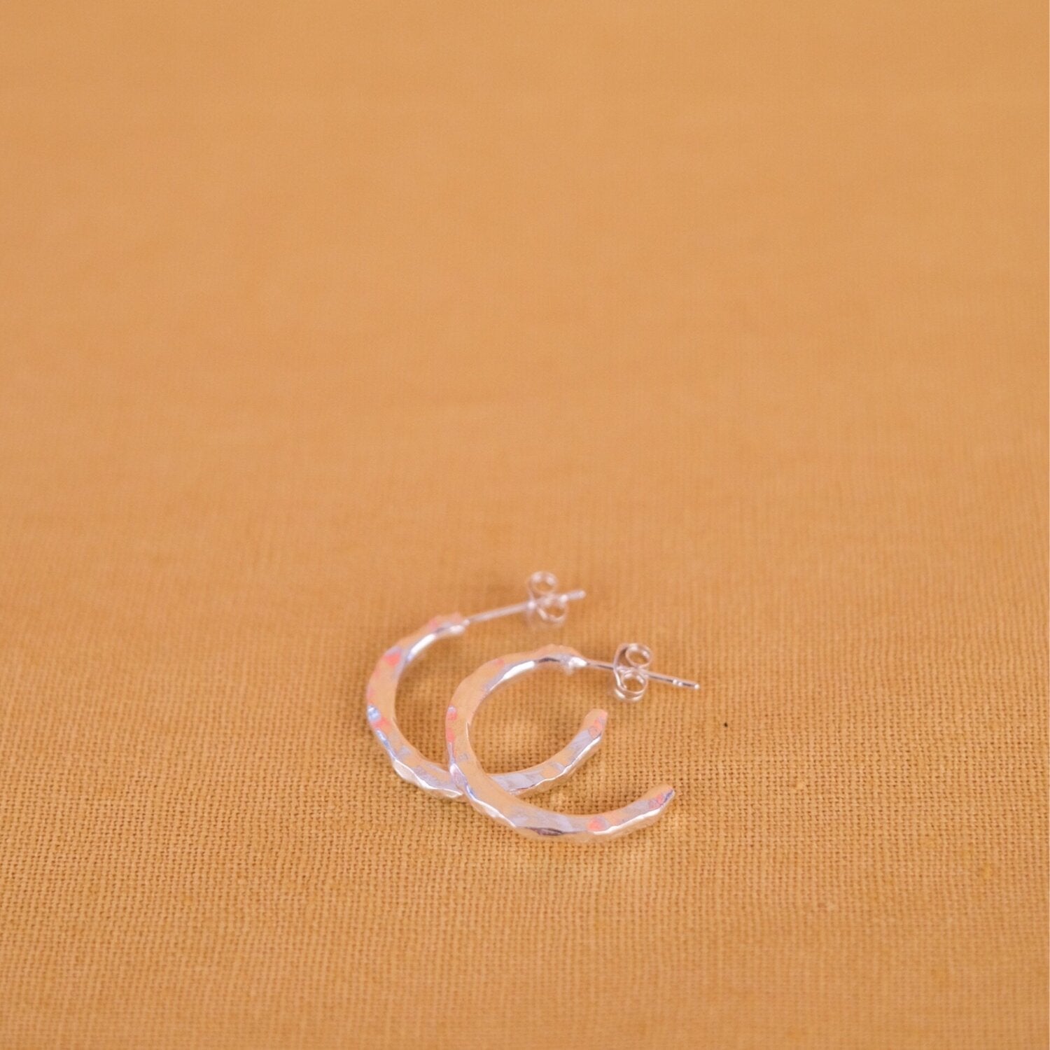 Close up of small silver hoop earrings with a textured surface