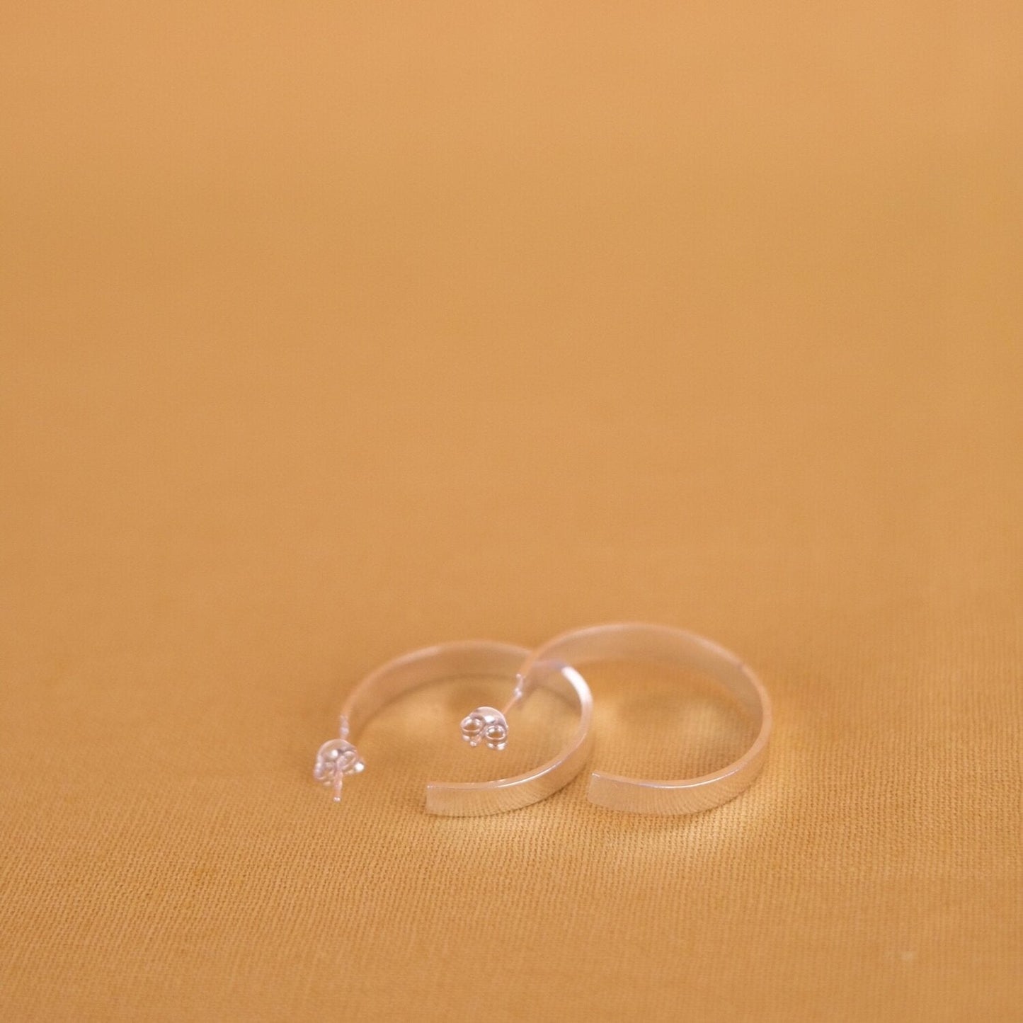 Close up of medium size flat hoop silver earrings