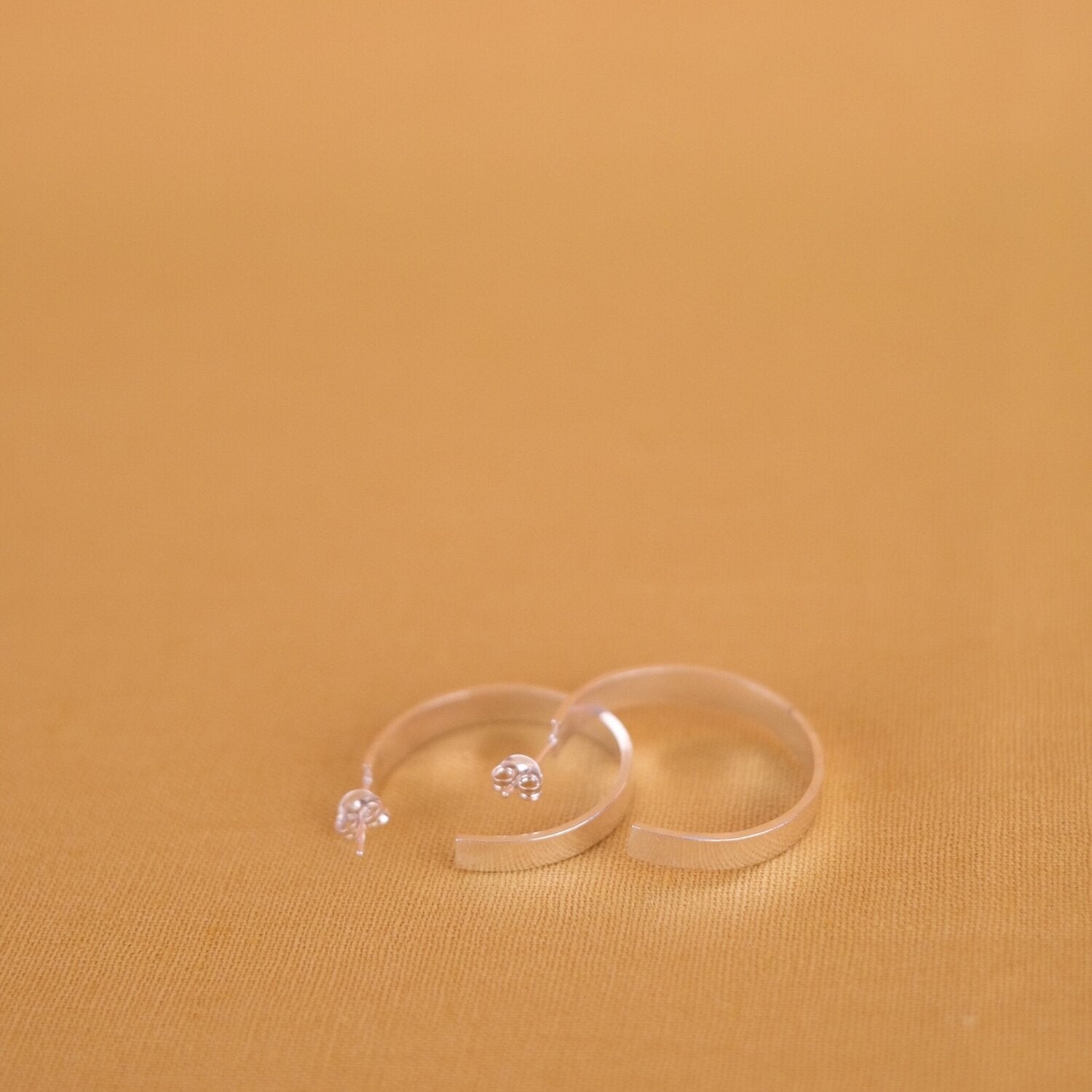 Close up of medium size flat hoop silver earrings