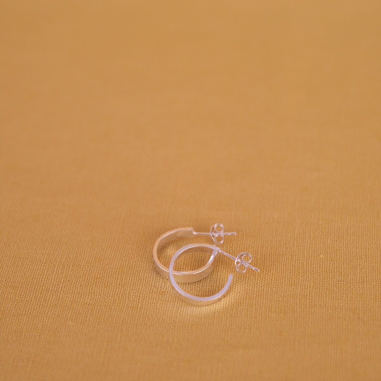 Close up of small, thick silver hoop earrings