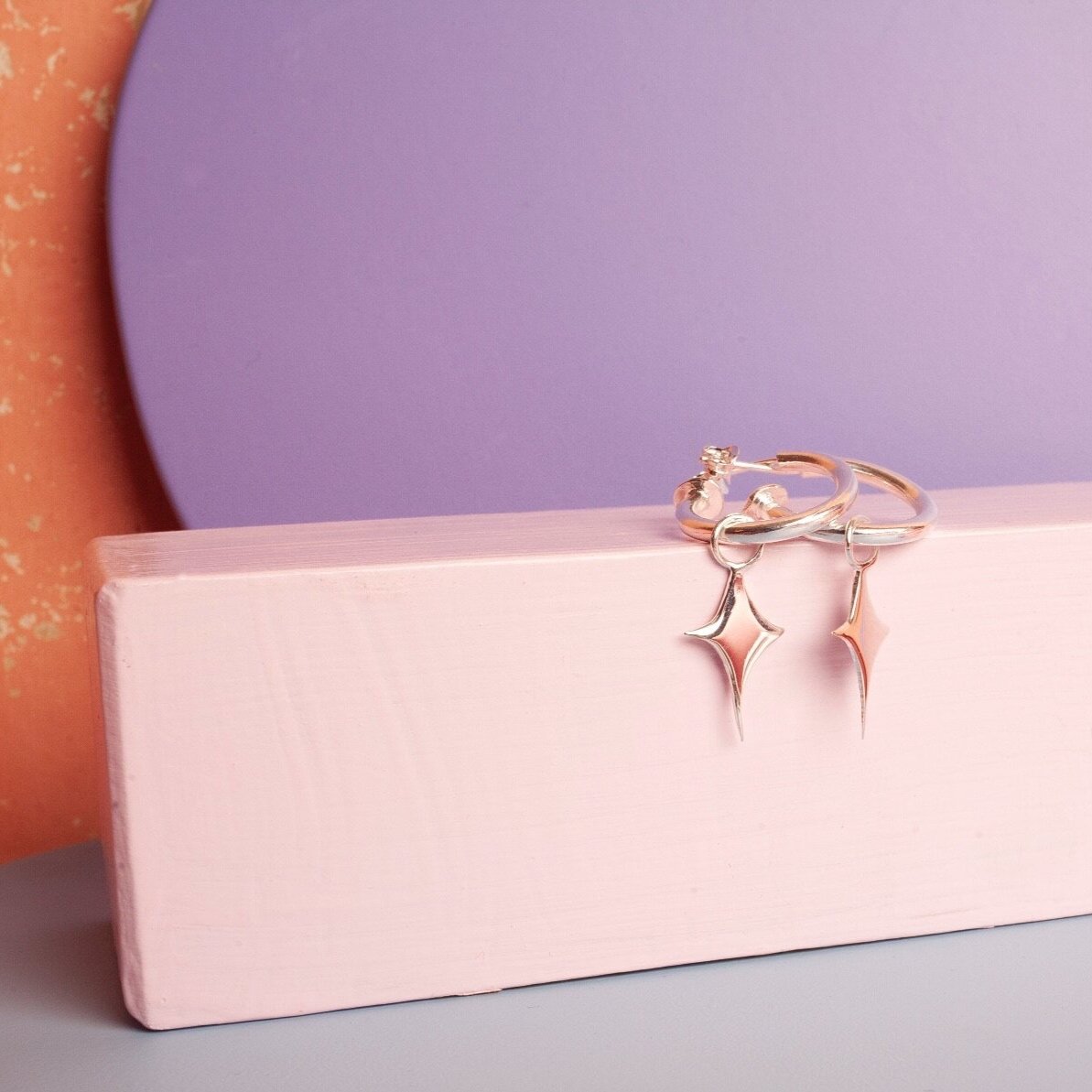 Small silver hoop earrings with a star shaped charm 