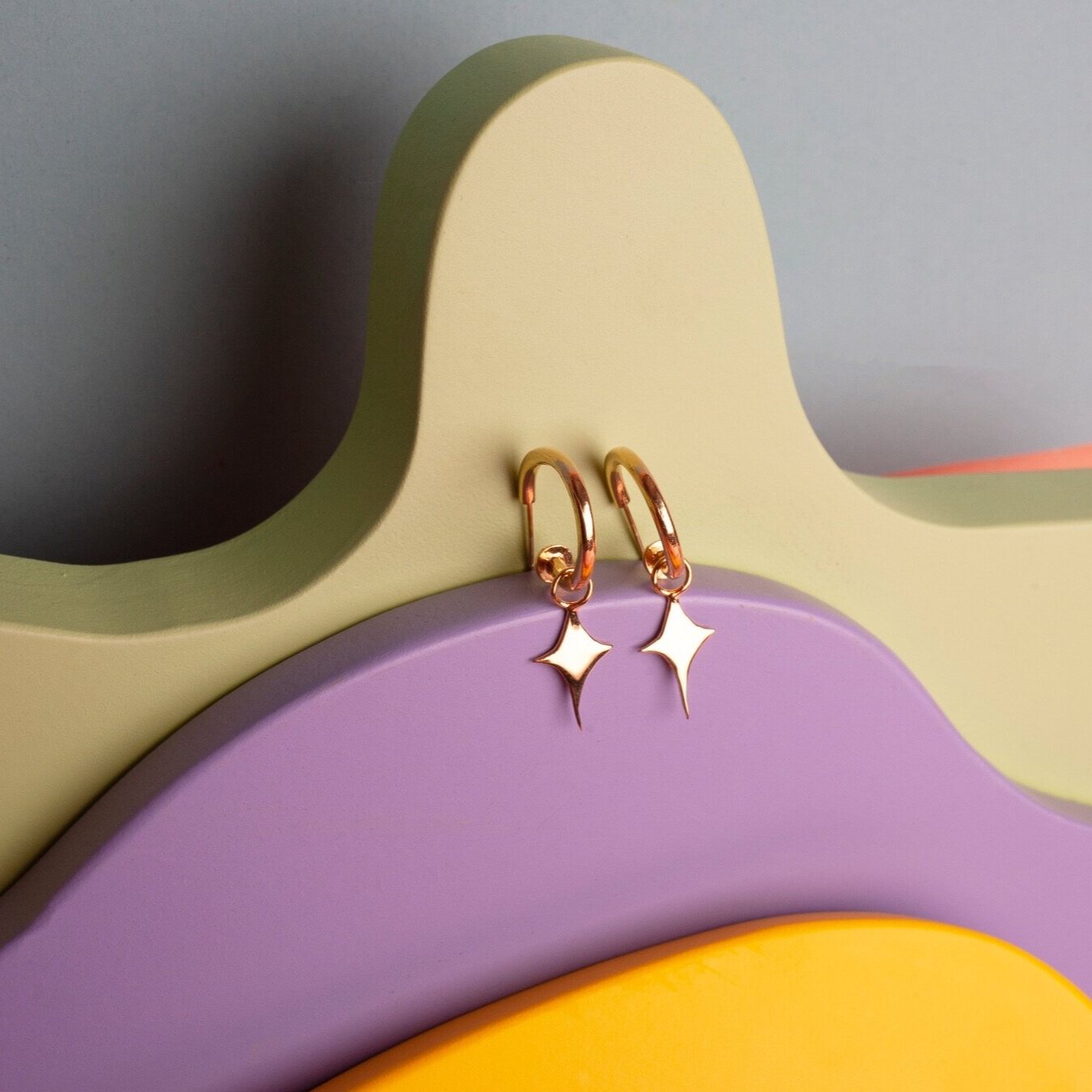Small gold hoop earrings with a star shaped charm 